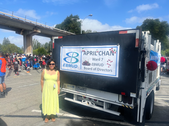 April Chan at the San Leandro Cherry Festival beside a campaign banner