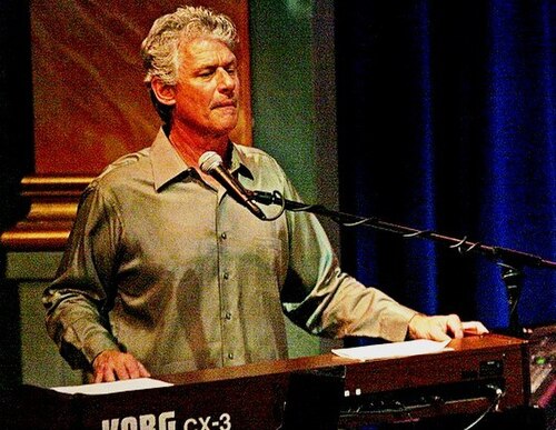 Ozzie Ahlers singing and playing keyboards onstage